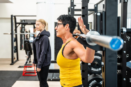 Personal trainer Tiina Huuskonen levytangon kanssa Treenitehtaan kuntosalilla Turussa